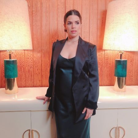 Actress America Ferrera in a black dress and coat poses at her house.